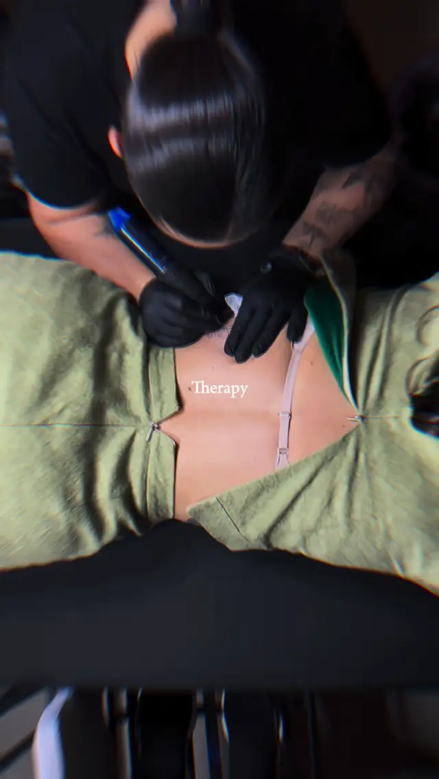 Overhead shot of Alba tattooing a word in fine script on a client's back
