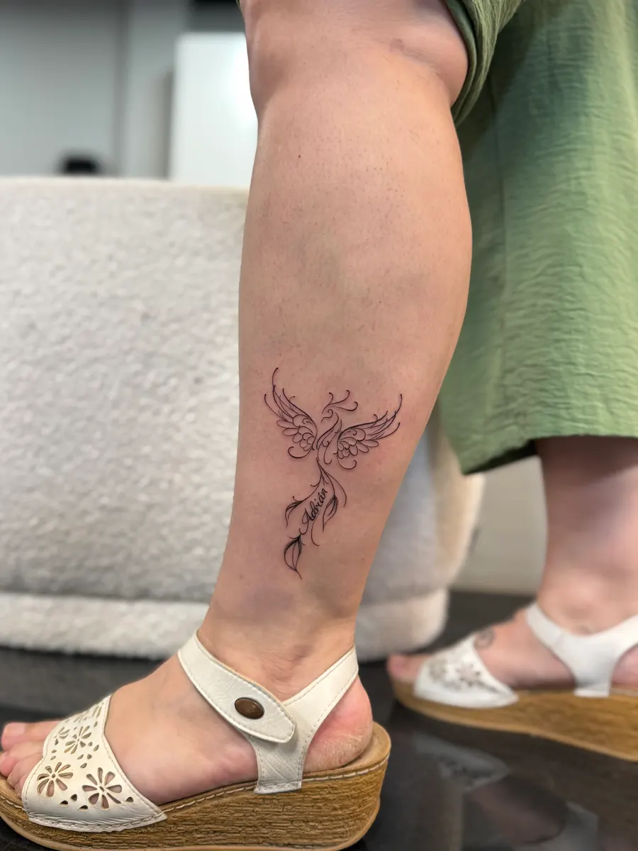 Ornamental phoenix in fine line tattooed on the calf, with the name Adrián woven into its tail